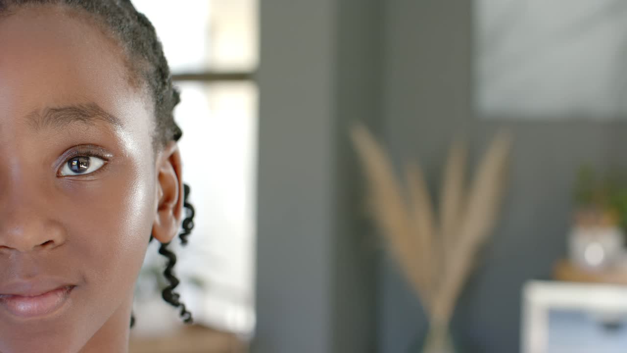 African youth holding gaze at camera, shifting into smiling from window light at home, copy space