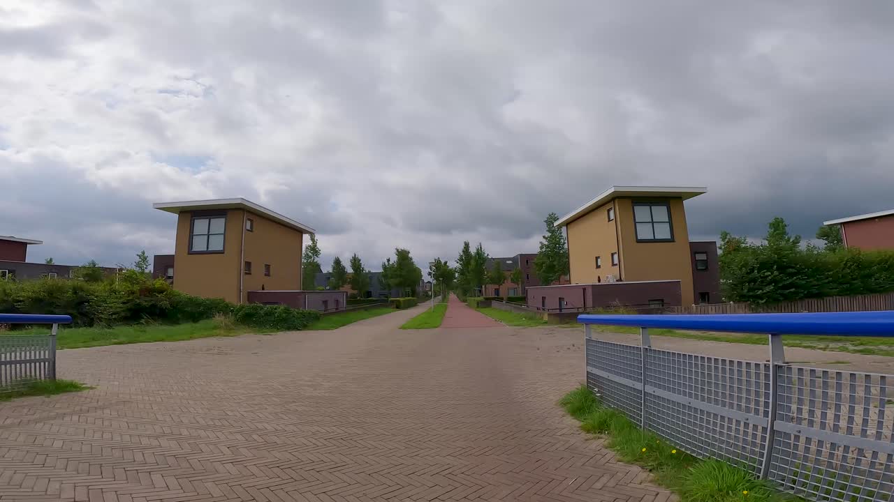 POV in bicicletta attraverso un moderno quartiere residenziale con un ponte