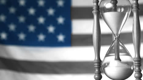 Sand-flowing-through-hourglass-with-american-flag-in-selective-black-and-white