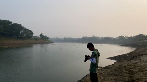 photographer capturing polluted river in bangladesh on foggy day using camera