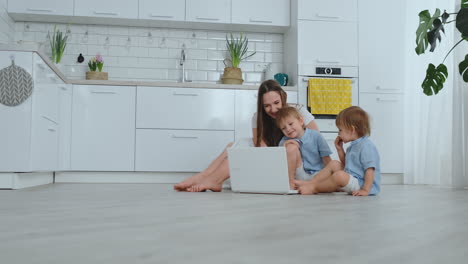 Schöne-Moderne-Junge-Familie,-Die-Zu-Hause-Auf-Dem-Boden-Liegt-Und-Etwas-Am-Laptop-Macht