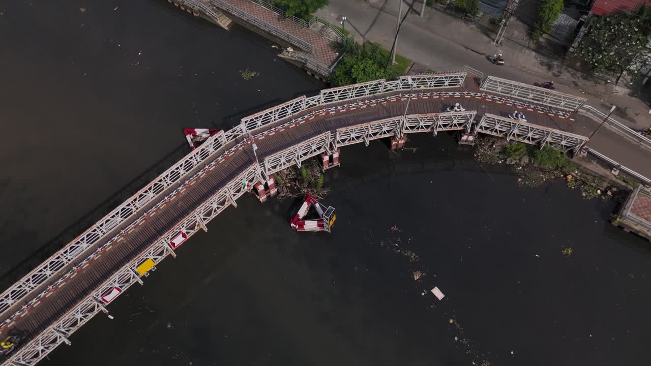 Small bridge used by motorcycles to cross a canal in Ho Chi Minh City, Vietnam. Top down shot tracking bikes on the curved bridge on sunny day
