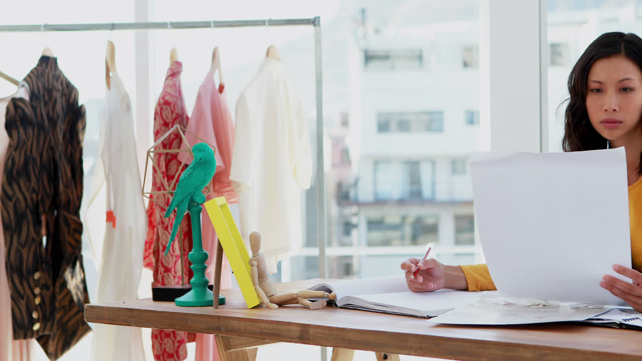 패션 디자이너가 책상 4k에 책을 쓰고 있습니다.