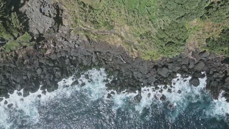 Top-down-view-of-waves-crashing-against-rugged-coastline-of-Santo-Antonio,-Azores-islands