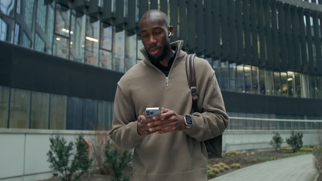 Man walking and using a smartphone in a city