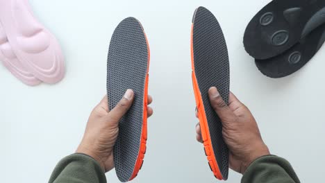 hands holding a pair of shoe insoles