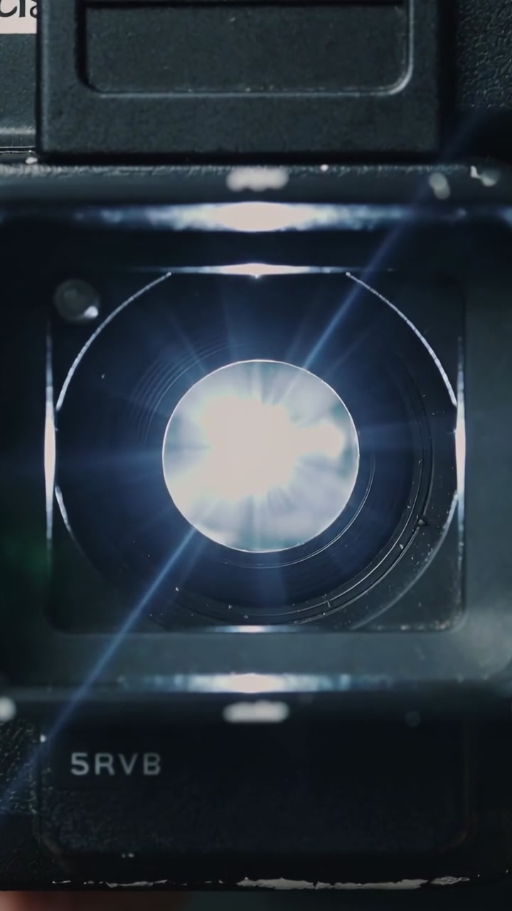 Vertical video: Bright light entering camera lens housing making flares and lighting iris, 5RVB
