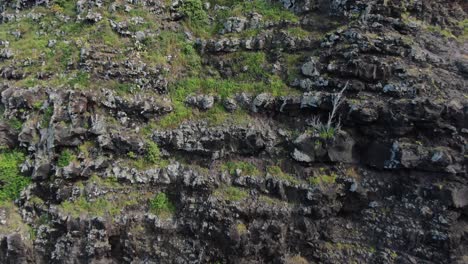 aerial pull away shot revealing the black and rugged volcanic sea cliffs of makapu'u point lighthouse in oahu