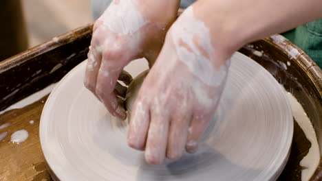 close up view of hands of a clerk modeling ceramic piece on a potter wheel in a workshop 1