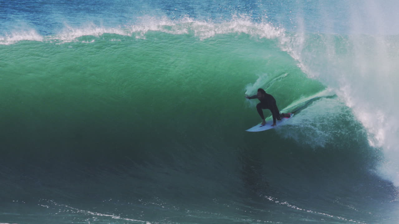 Wave collapses around surfer locked in pocket of fast-breaking green barrel