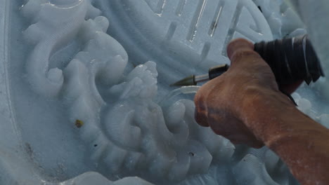 Hands-of-sculptor-carving-and-detailing-white-marble-stone-using-hand-tool,-close-up-shot,-Da-Nang-city,-Vietnam