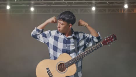 기타 미소를 짓고 무대에서 근육을 구부리는 아시아 십대