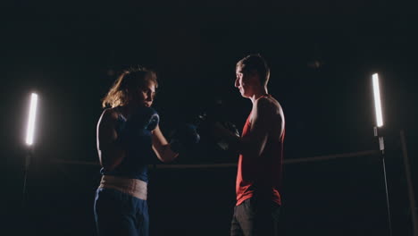 mujer golpea los guantes de enfoque en el gimnasio de boxeo