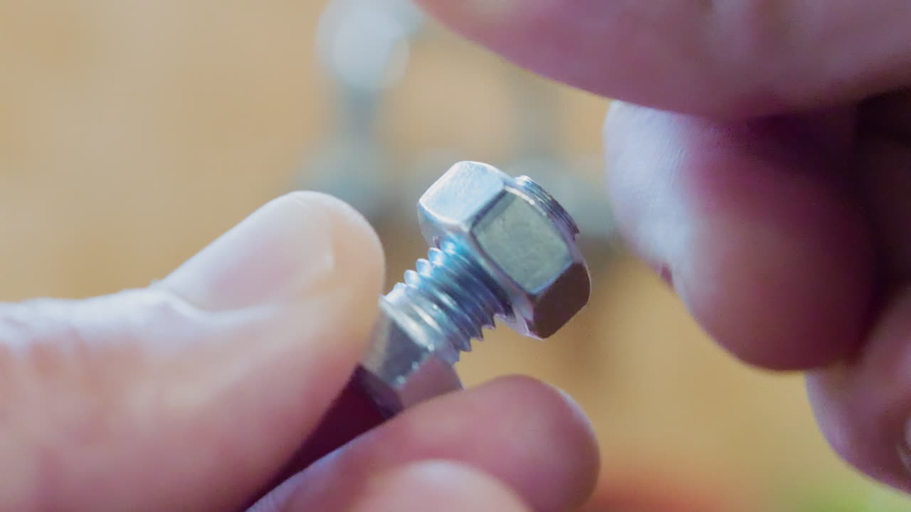 성인 백인 남성 손가락이 육각형 나사에 시계 방향으로 볼트를 고정합니다.