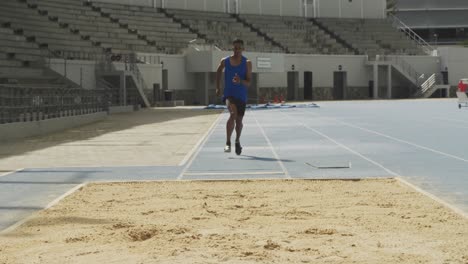 vista frontal de un atleta de raza mixta haciendo un salto de longitud