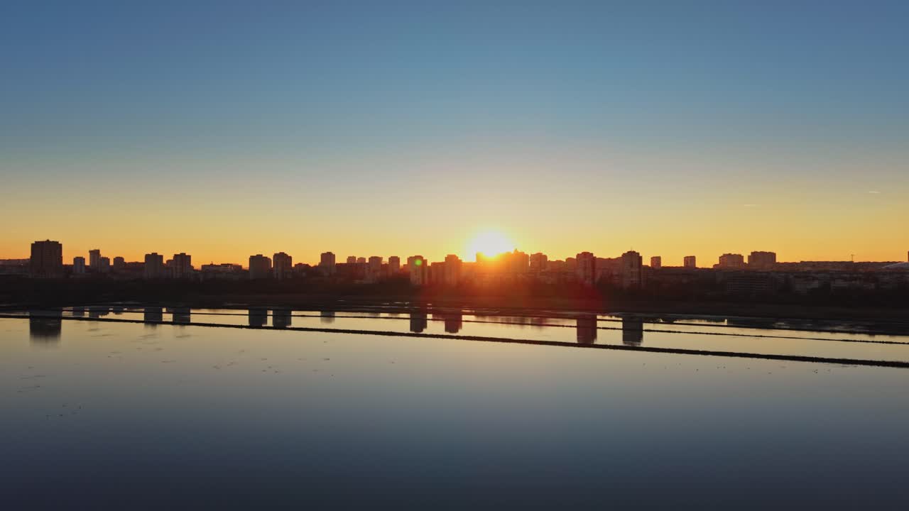 Sunrise over city skyline near water in salt industry setting