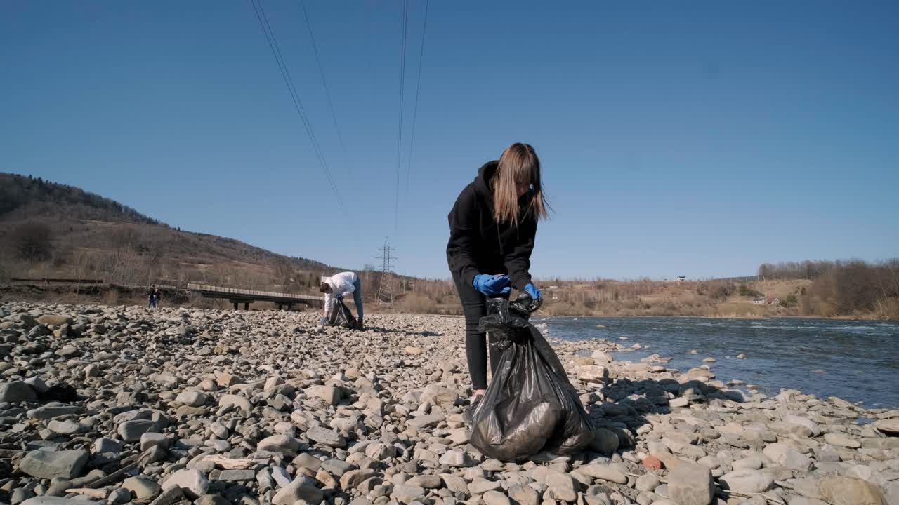 trabajo en equipo limpiando plástico en la playa. voluntarios recogen basura en una bolsa de basura. contaminación plástica y concepto de problema ambiental. limpieza voluntaria de la naturaleza del plástico. ecologización del planeta