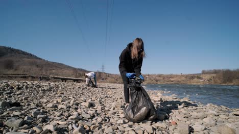 teamwork cleaning plastic on the beach. volunteers collect trash in a trash bag. plastic pollution and environmental problem concept. voluntary cleaning of nature from plastic. greening the planet