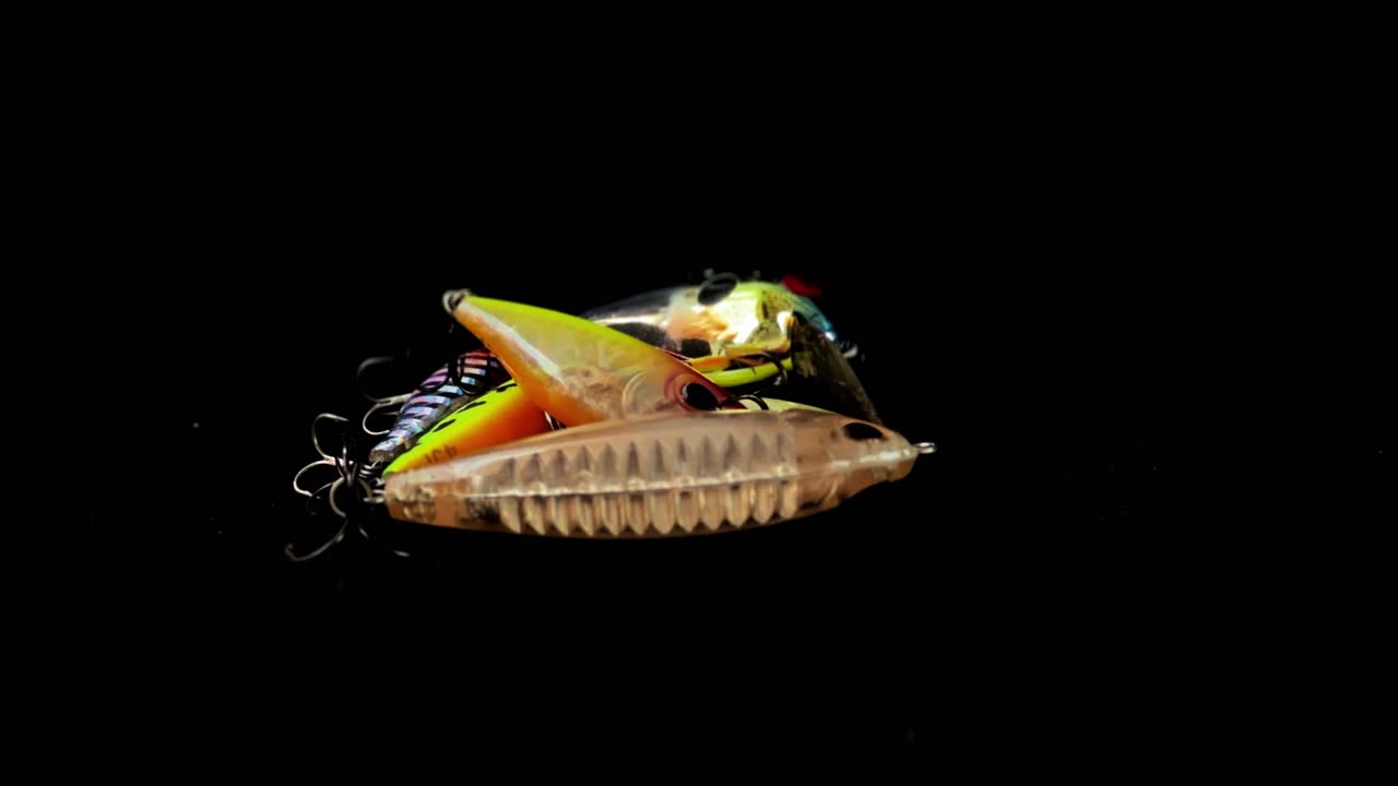 varios tipos de cebo de pesca artificial están apilados en un fondo negro