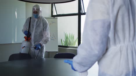 team of health workers wearing protective clothes cleaning the office using disinfectant sprayer