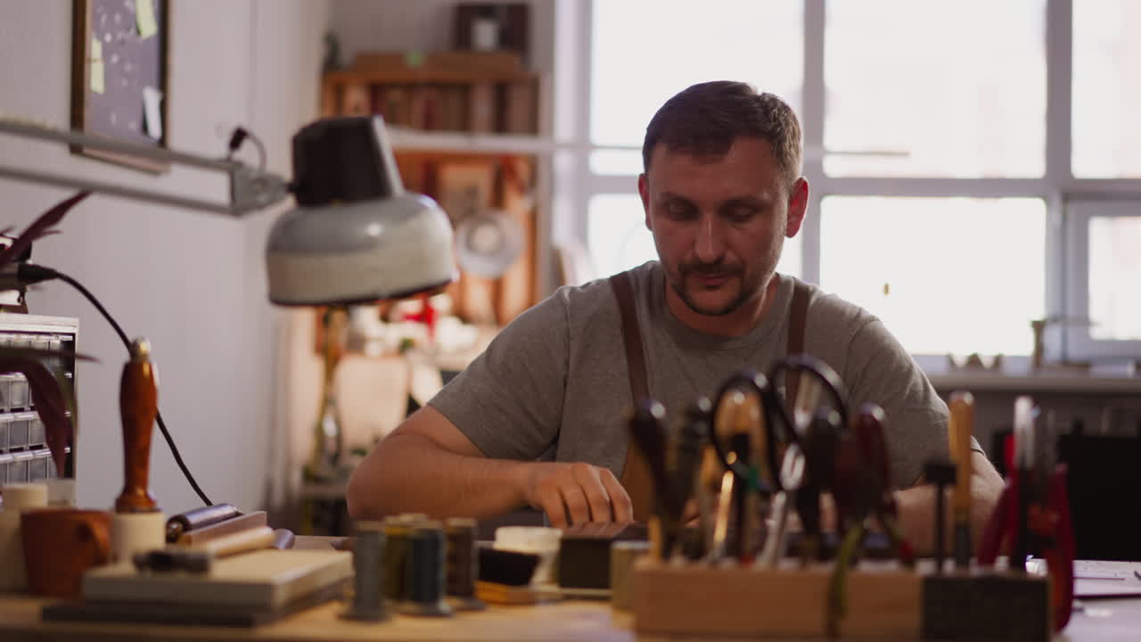 Leathersmith turns on lamp processing leather in workshop