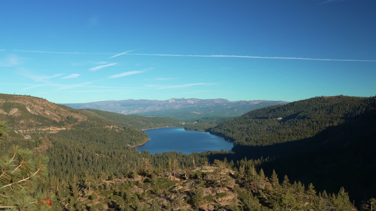 Paysage alpin panoramique montrant un lac et des collines boisées