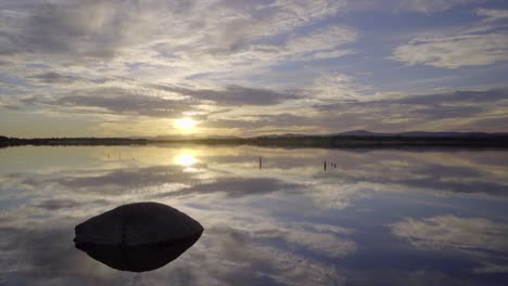 revealing a sunset on lake behind a rock