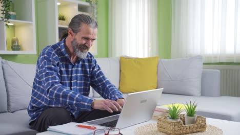 el anciano que trabaja desde casa en la computadora portátil está leyendo buenas noticias y regocijándose.