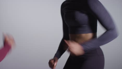 studio shot of two women wearing gym fitness clothing facing each other exercising running