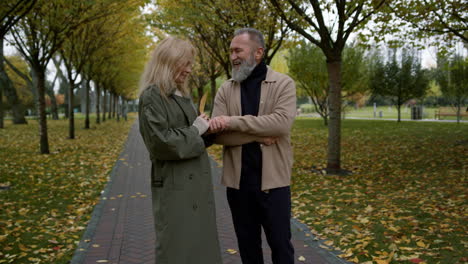 amantes felices y sonrientes hablando en el parque de otoño.