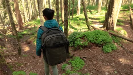 Hiking-woman-walk-with-a-hiking-backpack-in-spring-green-forest