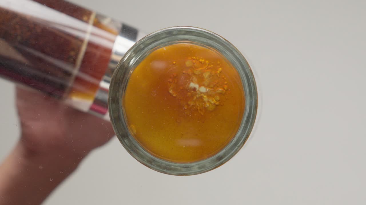 빨간색 갈색 액체 (아마도 커피 또는 차) 를 담은 유리 항아리와 기 장치를 들고 있는 손의 근접 시각.