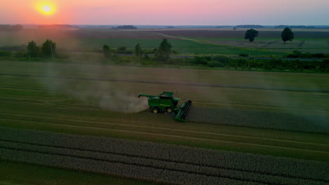 Aerial-drone-rotating-shot-over-a-combine-harvester-harvesting-across-a-ripe-corn-field-on-an-autumn-evening