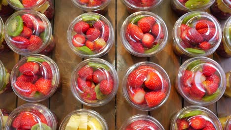 rows of delicious fruit cups: strawberries, kiwi, pineapple, and pomegranate