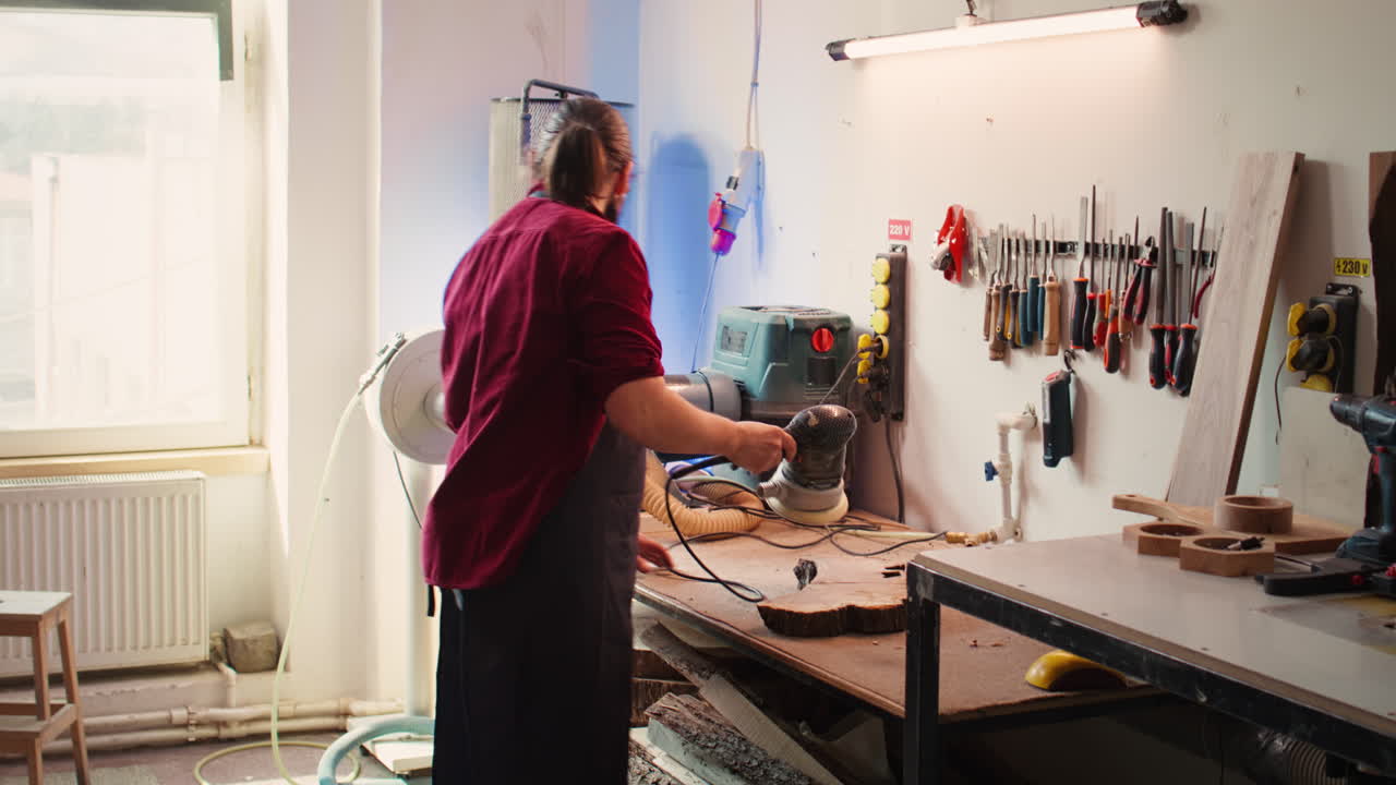 experto en carpintería que utiliza un engranaje de lijado orbital después de consultar los esquemas