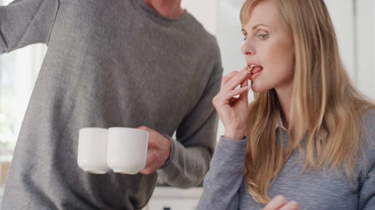 joven pareja feliz desayunando juntos marido sentado con su esposa en la mesa compartiendo la comida de la mañana en la cocina día en la vida 4k metraje