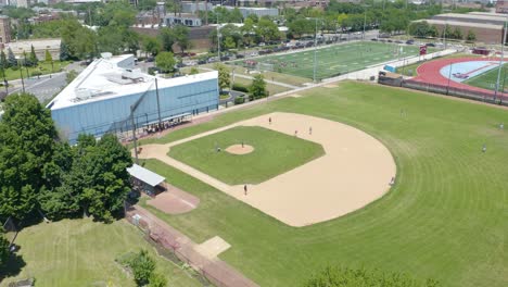 people playing baseball on field in city during summer - cinematic establishing shot