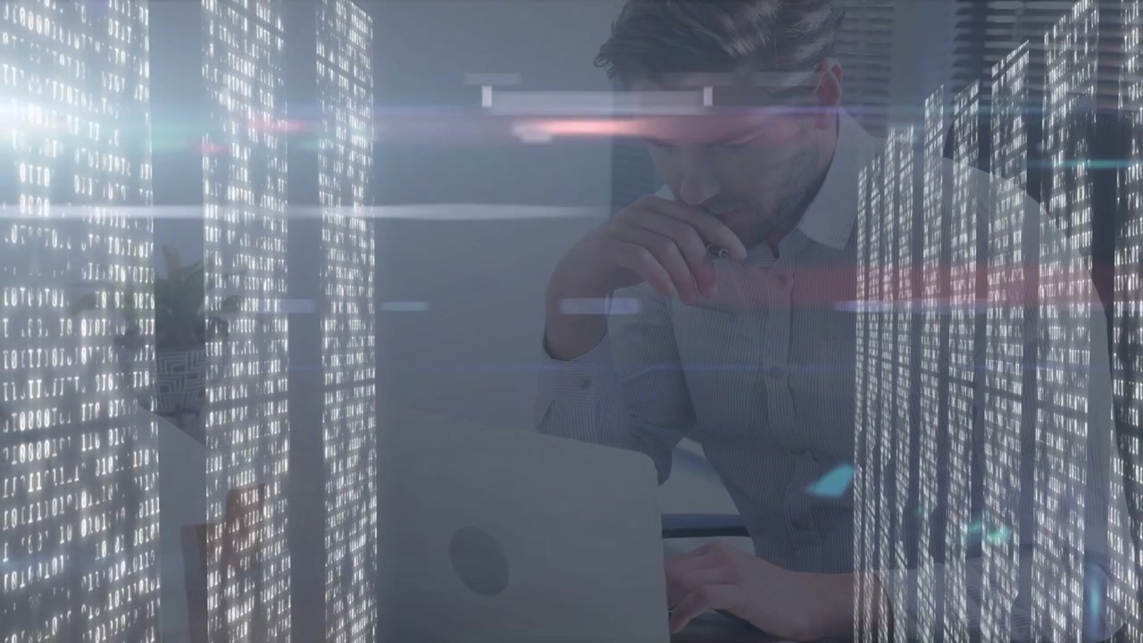 Man leaning at laptop and reviewing papers after data overlay appearing, using technology panels