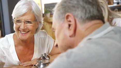 Senior-friends-looking-at-laptop-in-cafe-4k