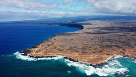 from above, the lava-scarred coastline of southern hawaii stretches into the horizon, as turquoise waters churn along the rugged edge of the windswept plateau