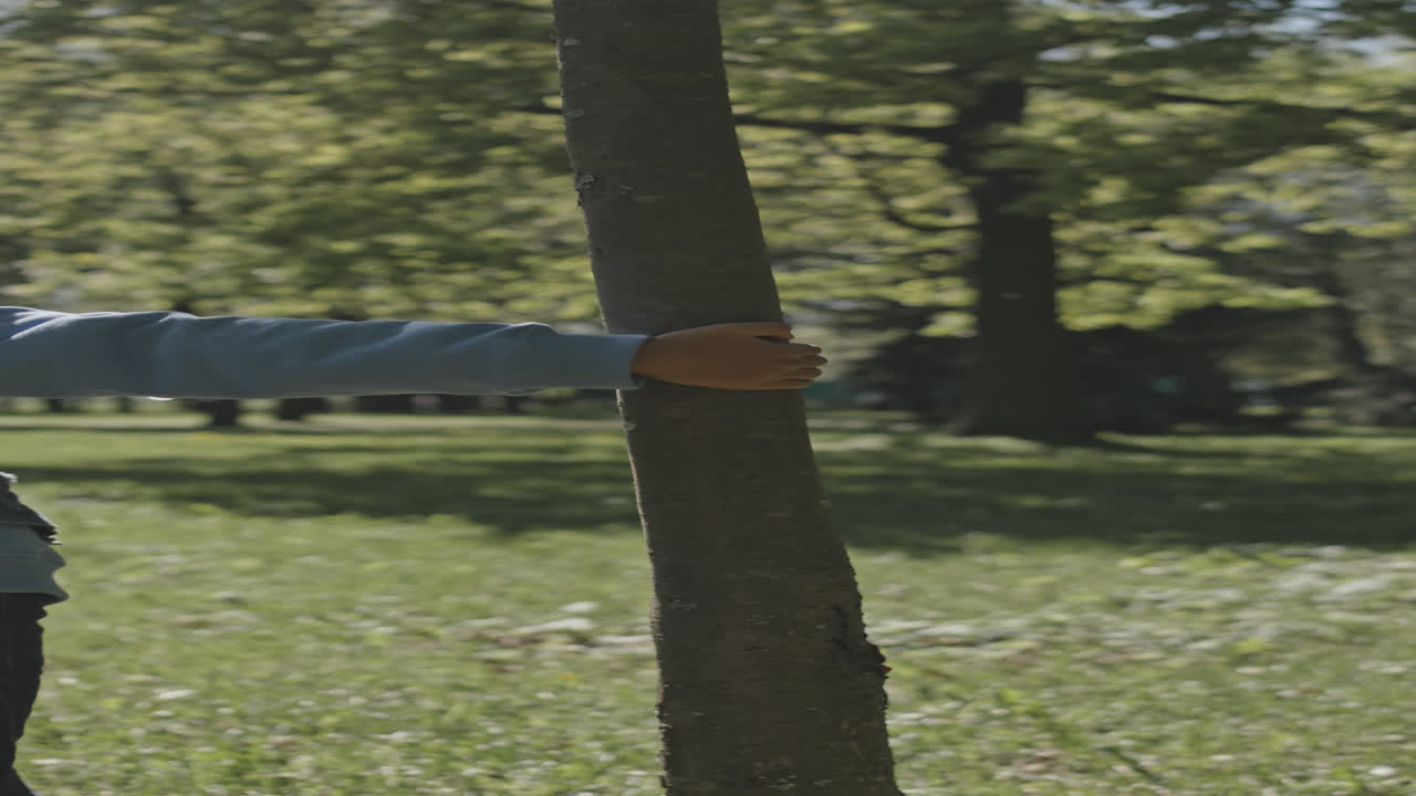 Little Boy Running around Tree in Park