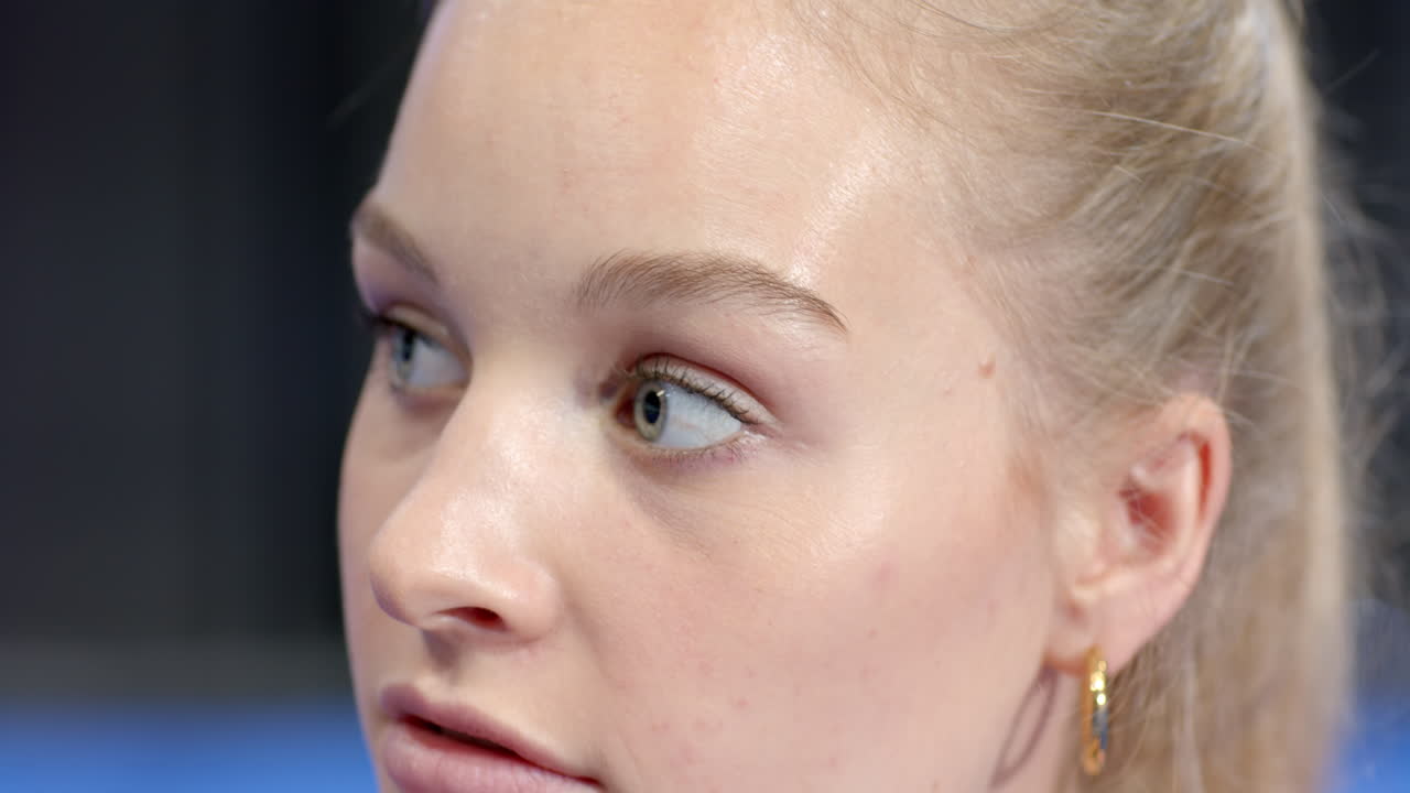 Young woman looking sideways with thoughtful expression during padel tennis match, at indoor court