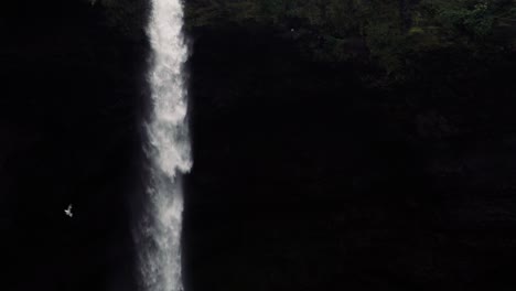 tomas en cámara lenta de una remota cascada islandesa con un hombre caminando hacia ella