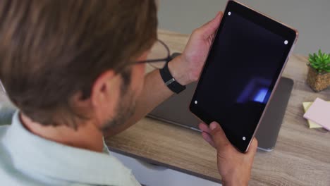 Caucasian-male-teacher-having-a-videocall-on-digital-tablet-in-the-classroom-at-school