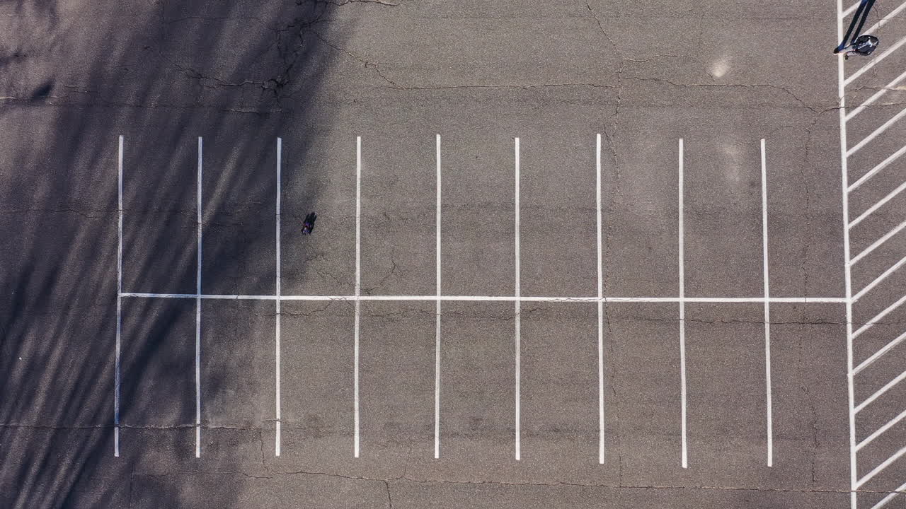 전기 원격 조종 자동차를 가지고 노는 남자와 빈 주차장 바로 위를 내려다보는 높은 앵글 샷