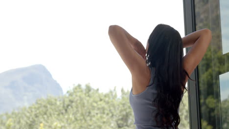 Happy-biracial-teenage-girl-stretching-on-sunny-balcony-in-the-morning,-copy-space,-slow-motion