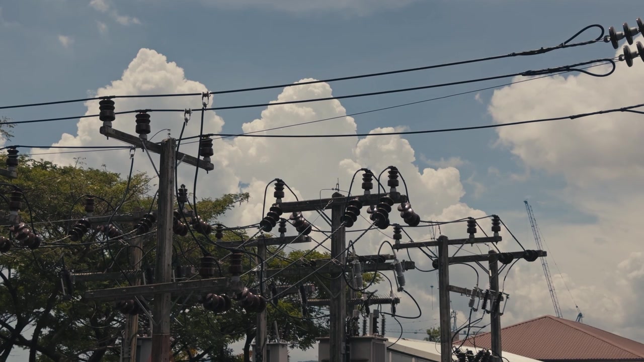 Close up view of electricity pole tops featuring transmission and distribution lines, silicone rubber insulators and power wires against the sky in an energy infrastructure scene.