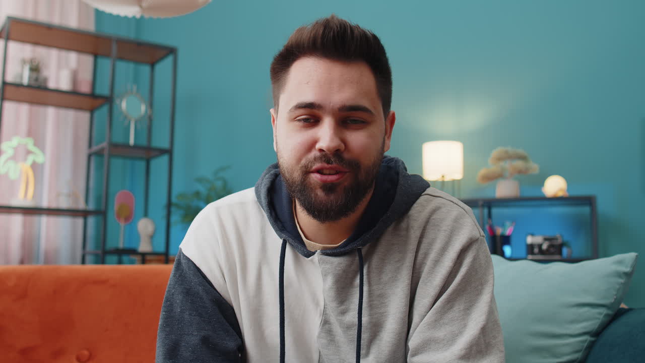 Caucasian man sitting on home couch looking at camera making video online webcam conference call