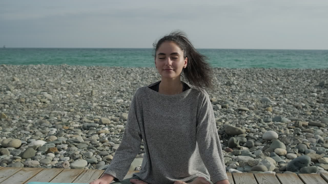 Kvinde mediterer på en stenstrand