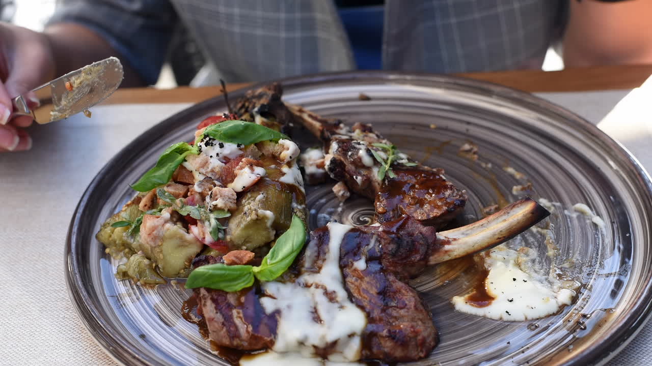 Close up of a woman eating ribs with vegetables at a terrace